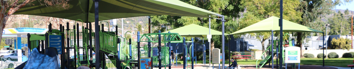 A photo of Johnny Carson Park playground, shade structure, and children playing.