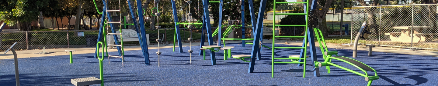 A photo of Johnny Carson Park playground, shade structure, and children playing.